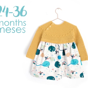 Puede incluir: Un vestido de punto amarillo con una falda estampada en blanco y azul. El vestido es para niños de 24 a 36 meses. El texto "24-36 months meses" está escrito en la imagen.