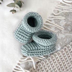 Puede incluir: Un par de botitas de bebé de punto suave en color azul claro. Las botitas tienen un diseño simple y clásico y son perfectas para mantener los pies pequeños calientes.