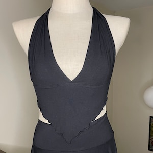 May include: A black halter top with a V-neckline and a ruffled hem. The top is made of a stretchy fabric and has a fitted silhouette.