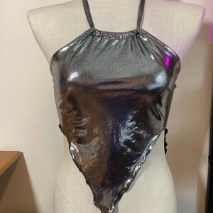 May include: A silver metallic halter top with a triangle shape and a ruffled edge.