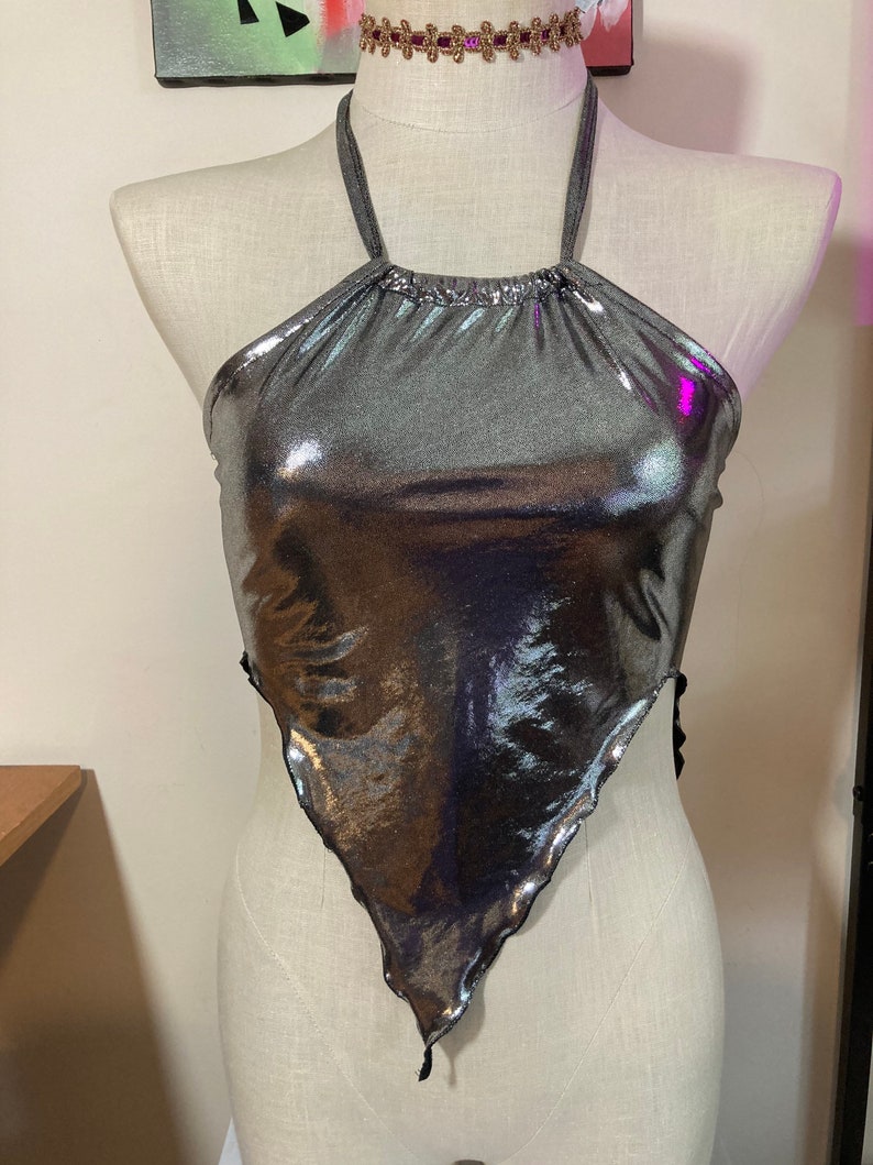 May include: A silver metallic halter top with a triangle shape and a ruffled edge.