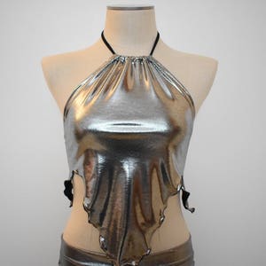May include: A silver metallic halter top with a gathered neckline and a draped, asymmetrical hem.