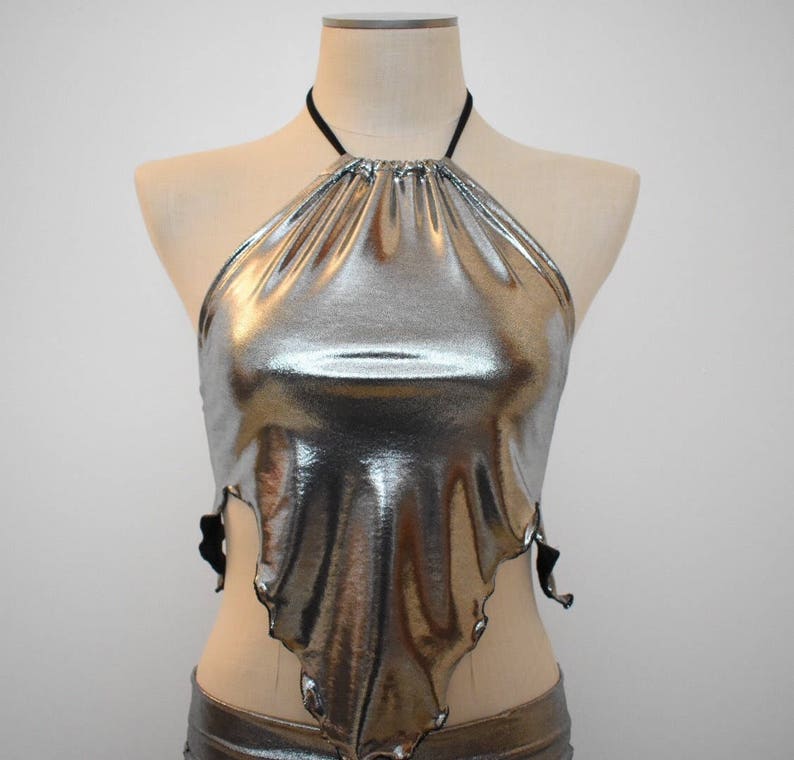 May include: A silver metallic halter top with a gathered neckline and a draped, asymmetrical hem.
