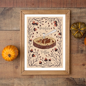 Può includere: Un'illustrazione incorniciata di un toffee da falò con uno sfondo marrone e un bordo decorativo di rami e ghiande. Il testo "Bonfire Toffee" è scritto in lettere nere.