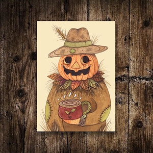 Puede incluir: Una ilustración caprichosa de un espantapájaros con cabeza de calabaza, que lleva un sombrero y sostiene una taza. El espantapájaros está vestido de marrón con detalles cosidos y un cuello de hojas. La taza roja presenta un diseño de hojas, con vapor saliendo de ella.