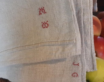 May include: Two white linen tea towels with red embroidered letters. The top towel has the letters "M" and "G" embroidered on it. The bottom towel has the letter "J" embroidered on it.