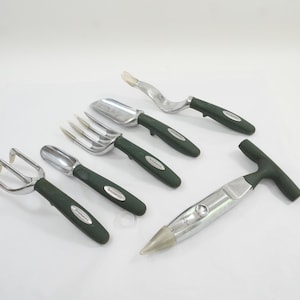 May include: A set of five gardening tools featuring silver metal heads and dark green ergonomic handles. The collection includes a three-tine hand rake, a small trowel, a fork, a weeder, and a T-handled bulb planter with a pointed metal tip.