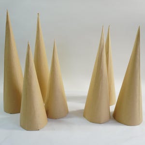 Könnte beinhalten: Eine Ansammlung von sieben beigefarbenen Papierkegeln unterschiedlicher Höhe. Die Kegel sind auf einer weißen Oberfläche angeordnet, mit ihren spitzen Spitzen nach oben. Schlichtes, minimalistisches Design.