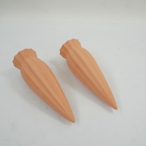 Pode incluir: Dois espigões de rega em terracota de cor laranja claro, em forma de cone com uma textura canelada e estriada. Cada espigão apresenta uma abertura superior larga que se estreita para uma ponta, concebida para a rega de plantas em vasos.