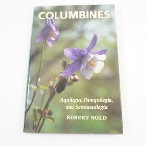 以下が含まれることがあります： 紫と白のオダマキの花の写真が表紙の「Columbines」というタイトルの本。表紙には「Aquilegia, Paraquilegia, and Semiaquilegia」というテキストと、著者名「ROBERT NOLD」も含まれています。