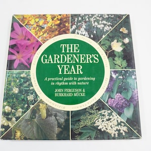 以下が含まれることがあります： 「The Gardener's Year」というタイトルの緑色の本で、副題は「A practical guide to gardening in rhythm with nature」で、ジョン・ファーガソンとバークハルト・ミュッケによるものです。表紙には、カラフルな花と植物の画像のコラージュが掲載されています。