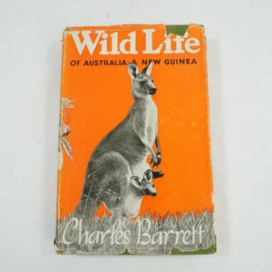 May include: Vintage book cover titled "Wild Life of Australia & New Guinea" by Charles Barrett. The cover features a kangaroo with a joey against an orange background. The book has a worn appearance.