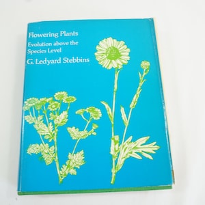 May include: A hardcover book titled "Flowering Plants" with a turquoise cover. The cover features white and green illustrations of flowers and text. The author's name, G. Ledyard Stebbins, is also printed on the cover.
