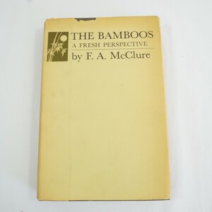May include: A vintage book titled "THE BAMBOOS A FRESH PERSPECTIVE" by F. A. McClure. The cover is a light yellow colour with the title and author's name in dark green. The book has a bamboo illustration.