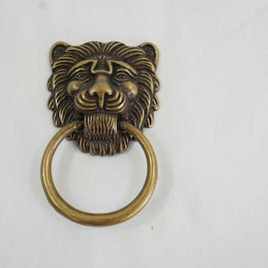 May include: A gold lion head door knocker with a ring pull.