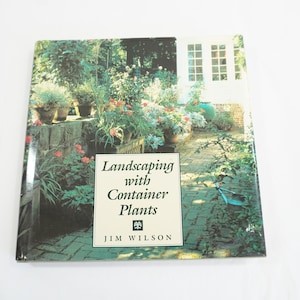 May include: A book titled "Landscaping with Container Plants" by Jim Wilson. The cover features a photo of a brick pathway lined with lush greenery and potted plants.