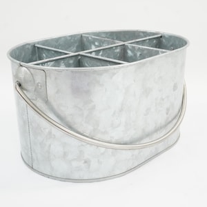 Pode incluir: Balde oval de metal galvanizado com seis compartimentos. O balde tem uma alça curva. O metal tem uma aparência texturizada. O design é simples e funcional, adequado para armazenamento ou exibição.