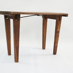May include: A small, vintage wooden table with a rectangular top and four tapered legs. The table is made of dark brown wood and has a simple, functional design. The table is approximately 24 inches long, 18 inches wide, and 28 inches tall.