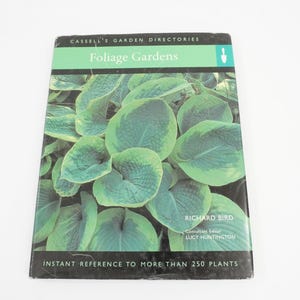 May include: A book titled "Foliage Gardens" with a green and white cover featuring a close-up of large, green leaves. The book is part of the Cassell's Garden Directories series and includes the author's name, Richard Bird, and the editor, Lucy Huntington.