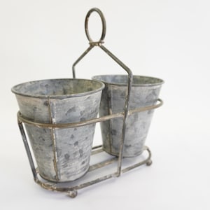 May include: A set of three ceramic mugs with a speckled, matte finish. The mugs are in shades of cream, light gray, and dark gray. Each mug has a simple, minimalist design and a rounded handle.