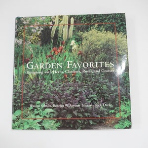 以下が含まれることがあります： ハーブ、つる植物、バラ、グラスを使ったデザインをテーマにした、緑豊かな庭園の風景が描かれた本の表紙。タイトル「GARDEN FAVORITES」は太字で表示され、サブタイトル「Designing with Herbs, Climbers, Roses, and Grasses」が続きます。著者の名前はタイトルの下に記載されています：Warren Schultz、Rebecca W. Atwater Briccetti、Rick Darke。