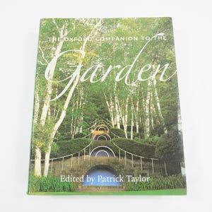 May include: A hardcover book titled The Oxford Companion to the Garden, edited by Patrick Taylor. The front cover features a photograph of a tiered stone garden structure with arched openings, surrounded by tall trees and lush green foliage.