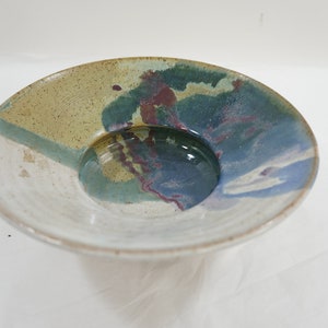 Peut inclure: Un bol en céramique avec un glaçage blanc et un motif abstrait bleu, vert et marron.