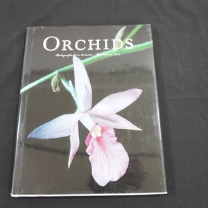 以下が含まれることがあります： 表紙にピンクと白の蘭の写真が載っている「Orchids」というタイトルの本です。