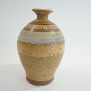 Könnte beinhalten: Eine kleine, braune Keramikvase mit rundem Körper und schmalem Hals. Die Vase hat eine mehrfarbige Glasur mit braunen, weißen und hellrosa Streifen.