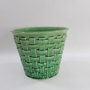 以下が含まれることがあります： 編みかごのデザインが施された緑色のセラミック製のプランター。プランターは釉薬がかけられており、滑らかな仕上がりです。