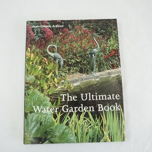 Op de afbeelding: De omslag van het boek "The Ultimate Water Garden Book" van Jean-Claude Arnoux, met een vijver met groene planten en twee kraanvogelbeelden.