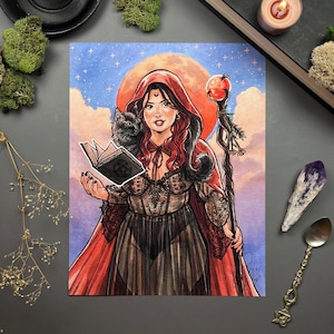 May include: A woman with red hair and a red hooded cloak stands in front of a full moon. She holds a book with a pentagram symbol and a black cat sits on her shoulder. She holds a staff with a red apple on top. The background is a blue sky with stars.