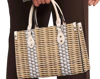 May include: A rectangular woven handbag with cream-colored handles and accents. The bag features two vertical rows of small, light-colored beads. The bag is held by a person wearing a black and white patterned jacket and brown pants.