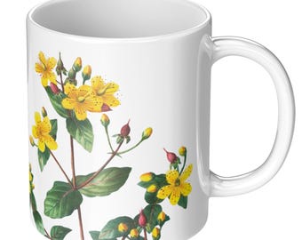 May include: White ceramic mug featuring a botanical illustration of yellow flowers, green leaves, and red buds. The floral design wraps around the mug, creating a nature-inspired aesthetic. The mug has a standard handle and a glossy finish.