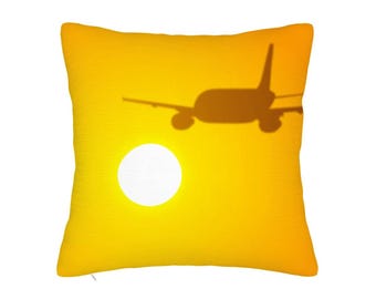 May include: Yellow decorative pillow with a graphic of an airplane shadow against a bright yellow background with a white circle resembling the sun. The pillow has a textured surface.