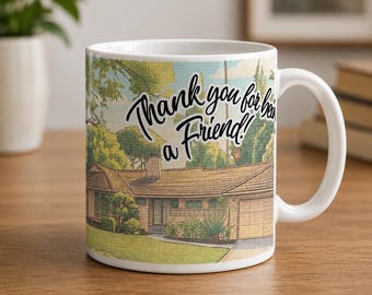 May include: A white ceramic mug featuring a colorful illustration of a suburban house with a lawn and trees. The text "Thank you for being a Friend!" is printed in black script across the upper portion of the design, centered above the house.