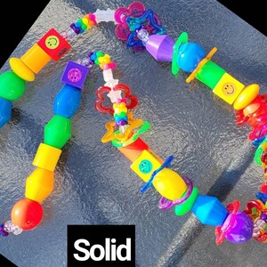 May include: A colorful beaded necklace with a variety of shapes and sizes. The beads are in a rainbow of colors, including red, orange, yellow, green, blue, and purple. Some beads have smiley faces. The word "Solid" is in the image.