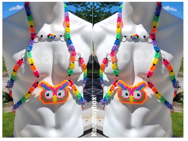 Peut inclure: Un harnais de corps compos&eacute; de perles en plastique multicolores dispos&eacute;es en motif arc-en-ciel. Le design comprend des anneaux m&eacute;talliques argent&eacute;s reliant les brins de perles et un pendentif central en forme de hibou fait de perles fusionn&eacute;es.