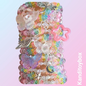 May include: A collection of colourful beaded bracelets adorned with butterfly, star, and wing charms. The bracelets showcase a spectrum of pastel hues, such as pink, yellow, blue, and green. The charms are silver and pink. The bracelets are stacked together.
