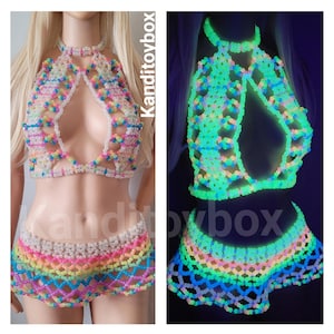 May include: A two-piece set consisting of a halter top and a skirt made from translucent, multi-colored plastic beads arranged in a lattice pattern. The set glows in the dark, emitting a bright neon green light. The text Kanditoybox is visible.