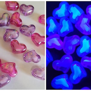 K&ouml;nnte beinhalten: Eine Sammlung transluzenter herzf&ouml;rmiger Perlen in Rosa- und Lilat&ouml;nen. Die Perlen haben eine gl&auml;nzende Oberfl&auml;che und leuchten unter Schwarzlicht, wodurch ein hellblaues inneres Leuchten entsteht. Ideal f&uuml;r Bastelarbeiten oder die Schmuckherstellung.