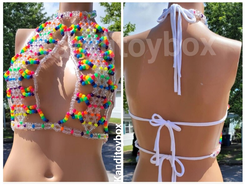 May include: A halter-style top constructed from clear and multi-colored rainbow plastic beads. The garment features a high neck, a cutout front design, and white fabric ties at the neck and back. The word Kanditoybox is visible on the image.