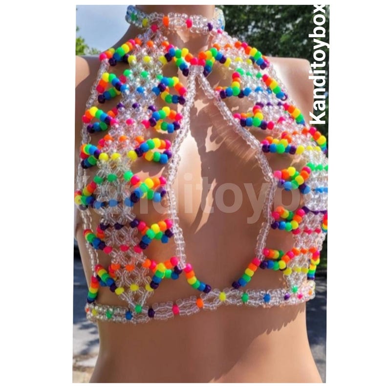 May include: A halter-style top constructed from clear and multi-colored plastic beads arranged in a geometric lattice pattern. The design features a high neck, a central cutout, and a band at the waist. The text Kanditoybox is visible on the side.