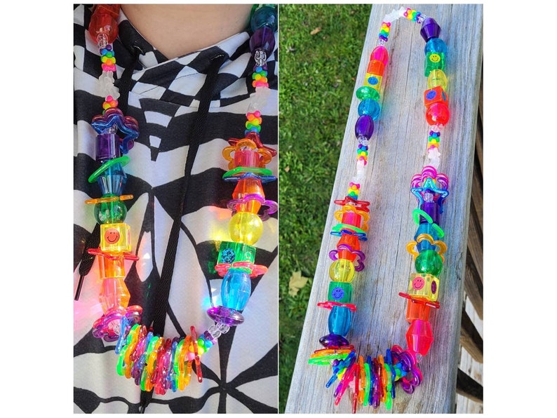 May include: A colorful necklace featuring a variety of transparent plastic beads in rainbow hues. The necklace includes smiley face beads, star-shaped elements, and other geometric shapes. The design is vibrant and playful, suitable for a fun, eye-catching accessory.
