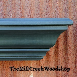 May include: A dark green wooden shelf with a decorative edge. The shelf is made of solid wood and has a distressed finish.