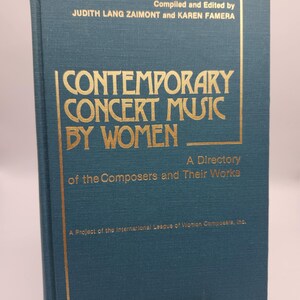 May include: A teal blue hardcover book with gold lettering titled "CONTEMPORARY CONCERT MUSIC BY WOMEN: A Directory of the Composers and Their Works". The book is a project of the International League of Women Composers, Inc. and was compiled and edited by Judith Lang Zaimont and Karen Famera.