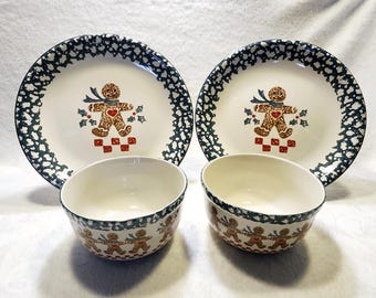 May include: Set of two white ceramic bowls and two white ceramic plates with a green and white speckled glaze. Each plate and bowl features a gingerbread man design with red accents.
