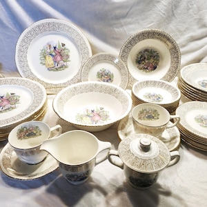 Puede incluir: Un juego de vajilla de porcelana vintage con borde dorado, con un patrón floral y un borde dorado. El juego incluye platos, cuencos, tazas y platillos.