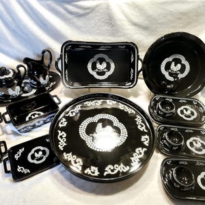 Könnte beinhalten: Ein Set aus schwarzen und weißen Keramikgeschirr mit einem Hahnendesign. Das Set enthält eine große Platte, eine kleinere Platte, eine Servierplatte, eine Kanne, eine Zuckerdose und vier kleine Schalen.