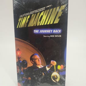 May include: A factory-sealed VHS tape titled The Time Machine: The Journey Back, starring Rod Taylor. The black cover features yellow text, a blue banner, and an illustration of a man operating a machine with colorful glowing lights.